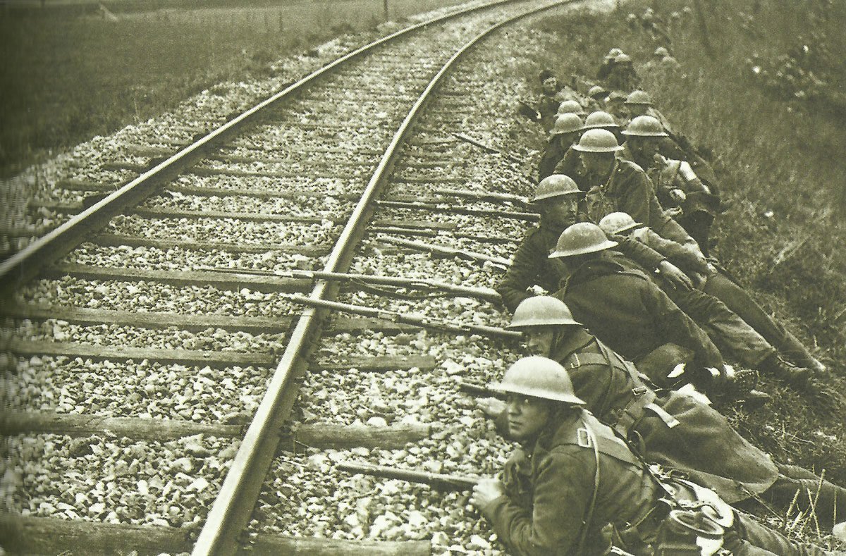 British troops take up position behind a railroad embankment