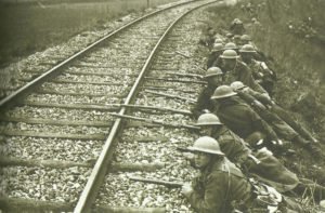 British troops take up position behind a railroad embankment 