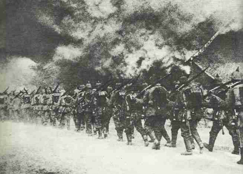 German infantry march through a burning French village